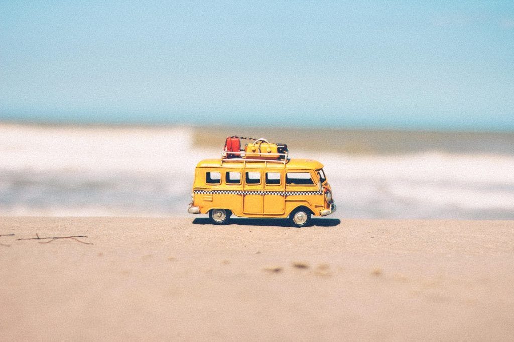 Lekebuss med bagasje på taket, på en sandstrand.